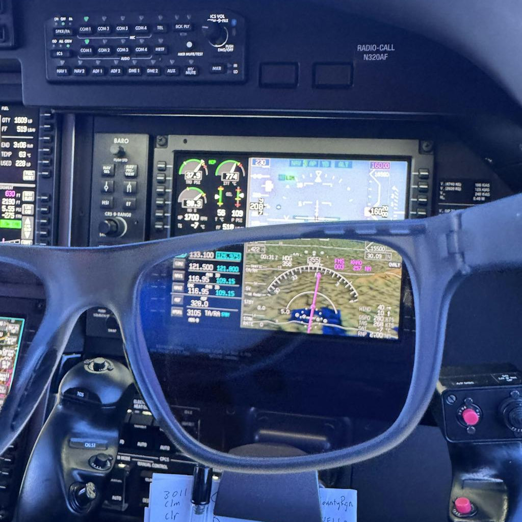Sunglasses reflecting a flight cockpit display with various controls and instruments.