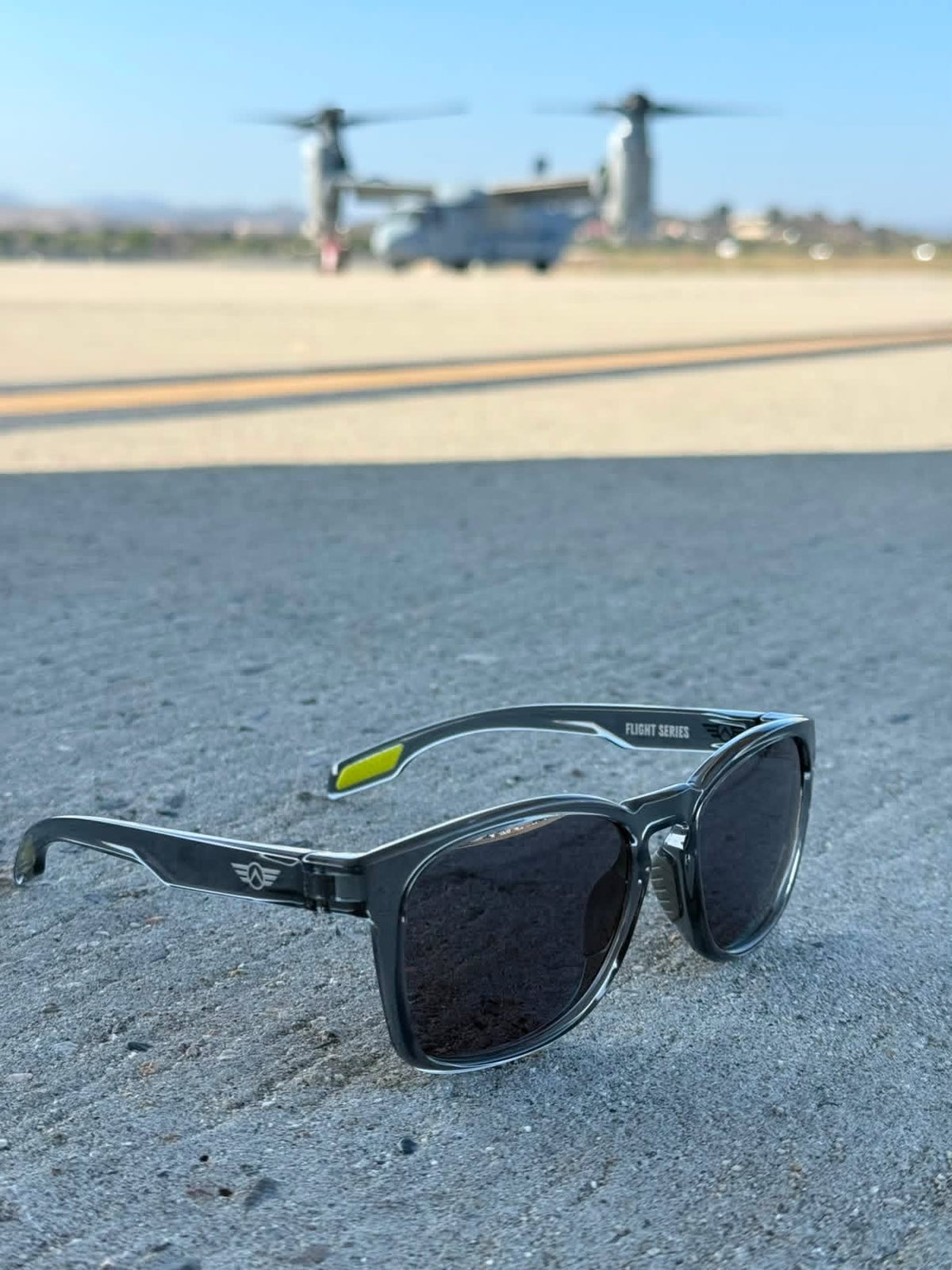 Sunglasses on a runway with military aircraft in the background