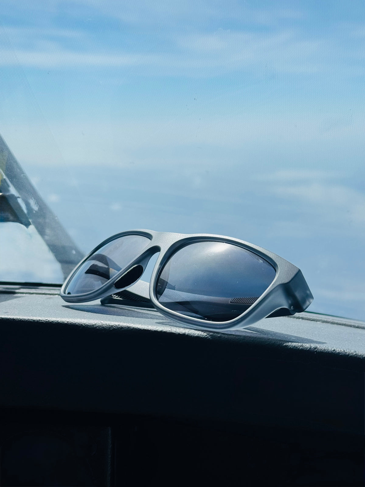 Sunglasses on a plane dashboard with a clear blue sky background