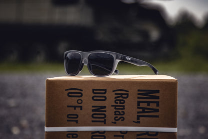 Sunglasses on a cardboard box with text in an outdoor setting