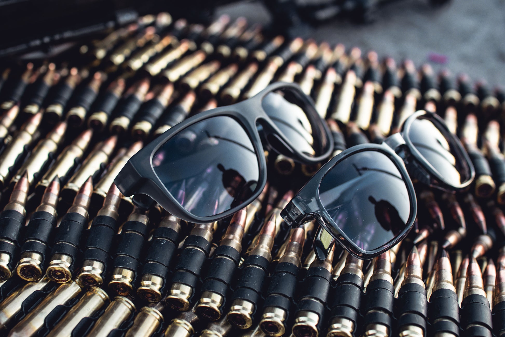 Black sunglasses on a bed of bullets with a reflective surface.