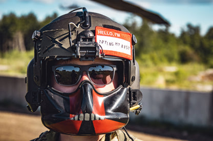 Person wearing a helmet with a reflective visor and a sticker on a blurred outdoor background